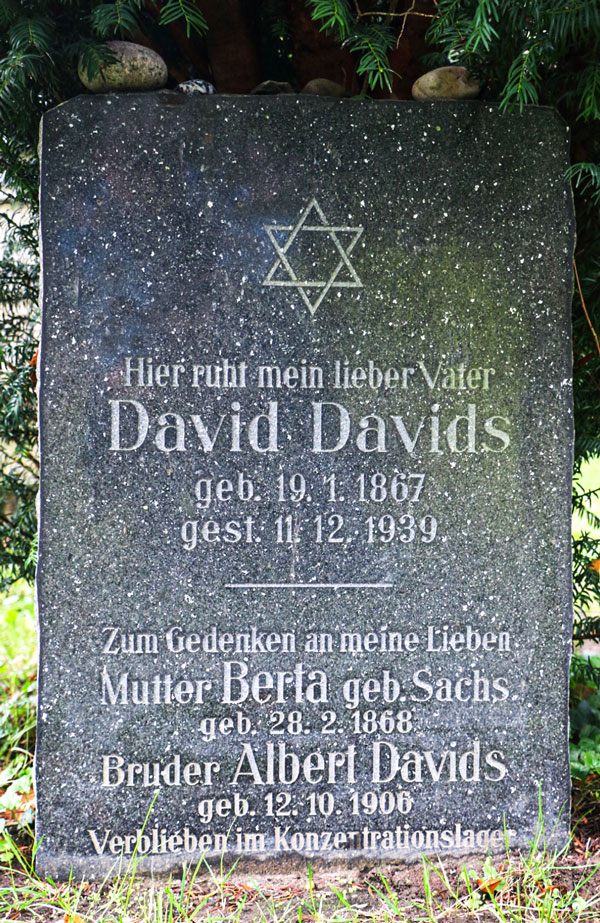 Schwarzer Grabstein mit eingemeißelter Schrift. Im oberen Teil ein Davidstern.