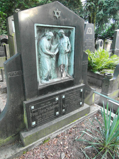 Großer Grabstein mit oxidiertem Kupferrelief von einer Frau und einem Mann. Darüber ein Davidstern, darunter die Namen der Verstorbenen.