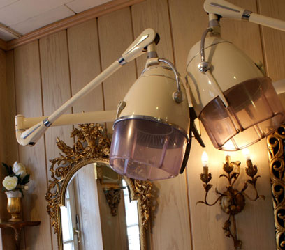 Wood-panelled room with mirror, sconce, and two drying hoods from the last century. Picture